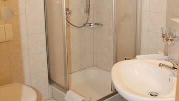Een badkamer met een toilet, een douche met glazen deur en een wastafel.