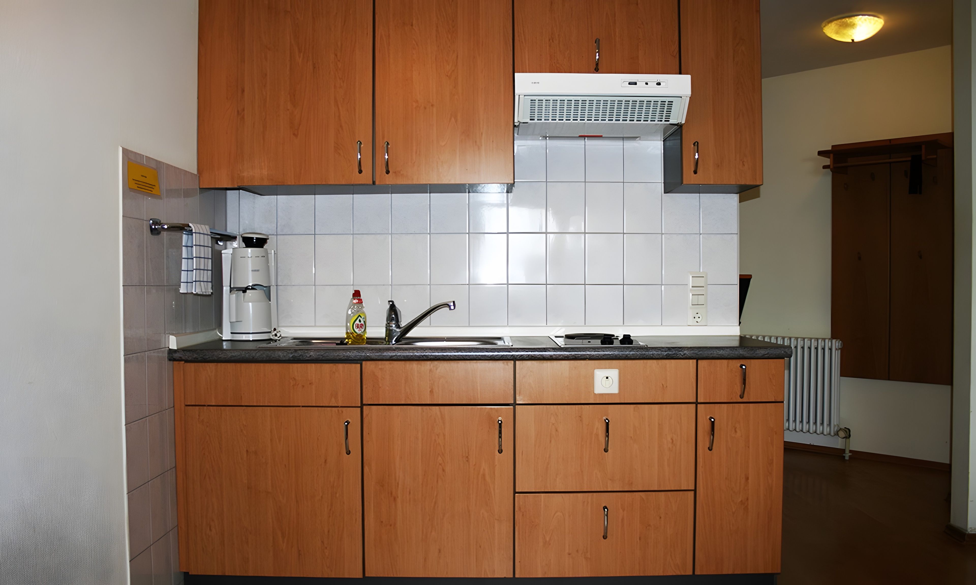 Eine Küche mit Holzausstattung, einem Backofen, einer Kaffeemaschine und einem Spülbecken.