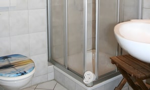 Une salle de bain comprenant des toilettes, un espace douche et un lavabo.