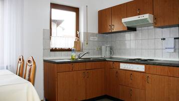 Una cucina con mobili in legno, forno a incasso e finestra con tenda.