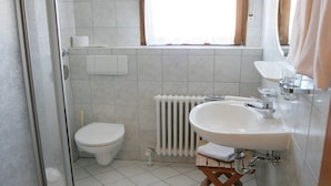 Un baño con inodoro, lavabo, ducha y ventana.