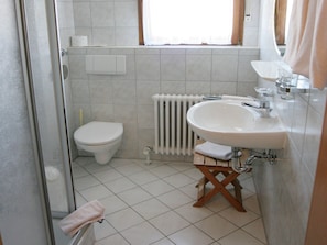 Un baño con inodoro, lavabo, ducha y ventana.