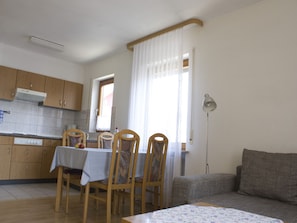 En kompakt bolig med spiseplads, tekøkken og sofa.