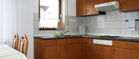 A kitchen with wooden cabinets, a built-in oven, and a window with a curtain.