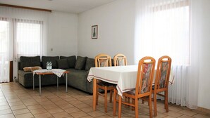 Un salon avec un canapé, une table à manger avec des chaises et une petite table sur laquelle se trouvent des bouteilles d’eau.