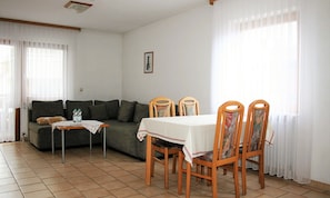 Una sala de estar con un sofá, una mesa de comedor con sillas y una mesita con botellas de agua.