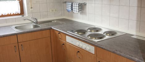 Keittiössä on puiset kaapit, ruostumattomasta teräksestä valmistettu pesuallas ja kaasuliesi.