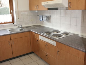 Una cocina con armarios de madera, un lavamanos de acero inoxidable y una estufa a gas.