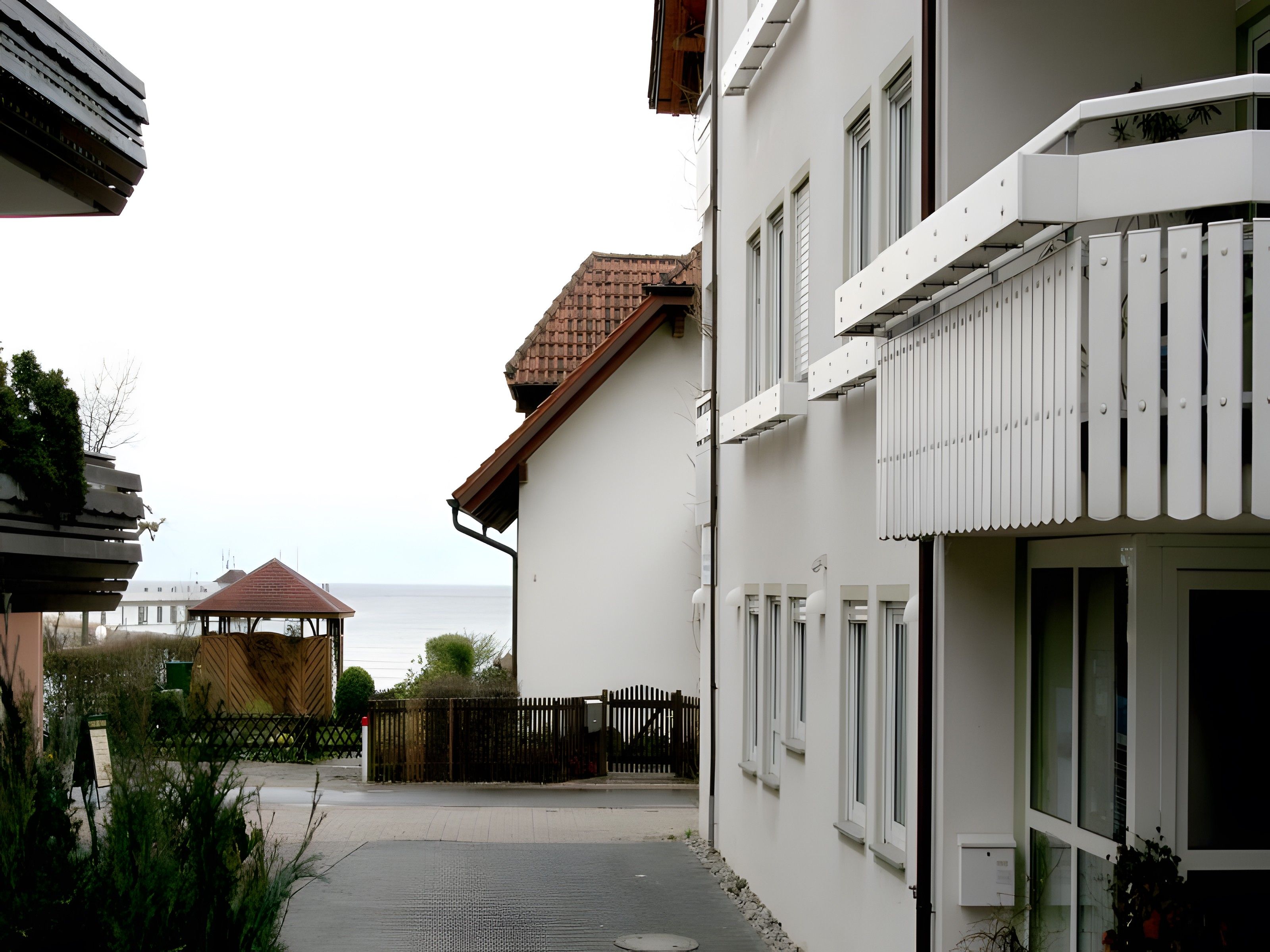 Ein Wohngebäude mit überdachter Terrasse, Meerblick und umzäunter Garten.