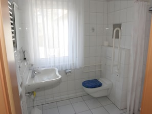 Un baño con lavamanos blanco, inodoro y zona de ducha.