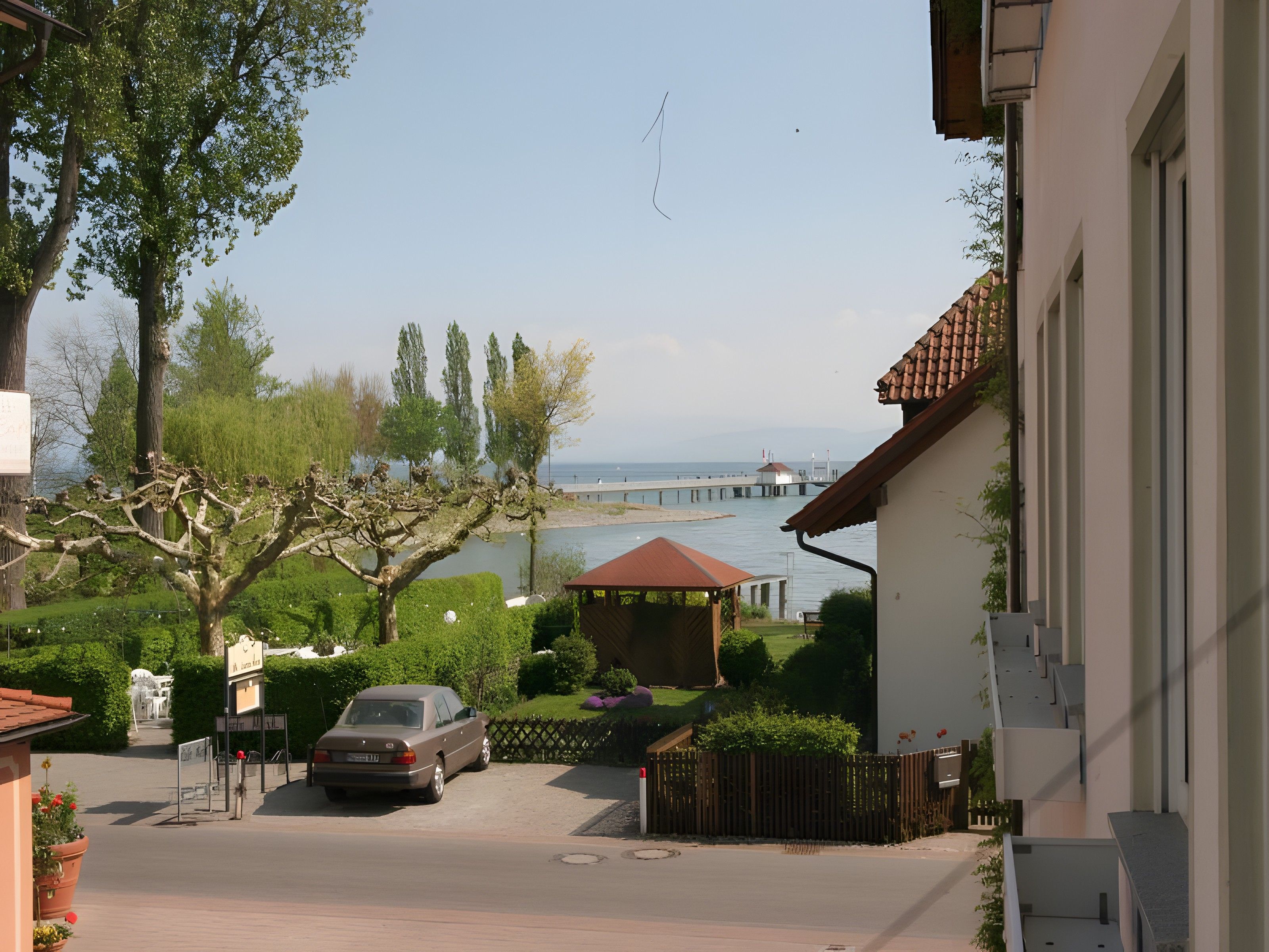Eine Wohnstraße mit einem parkenden Auto, einem Kiosk und Blick aufs Meer.