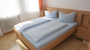 Un lit double avec un cadre en bois et une tête de lit, une table de chevet avec des tiroirs et un radiateur fixé au mur.