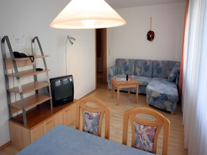 Ein möbliertes Wohnzimmer mit einer Couch, einem Fernseher, einem Tisch und einer Lampe.