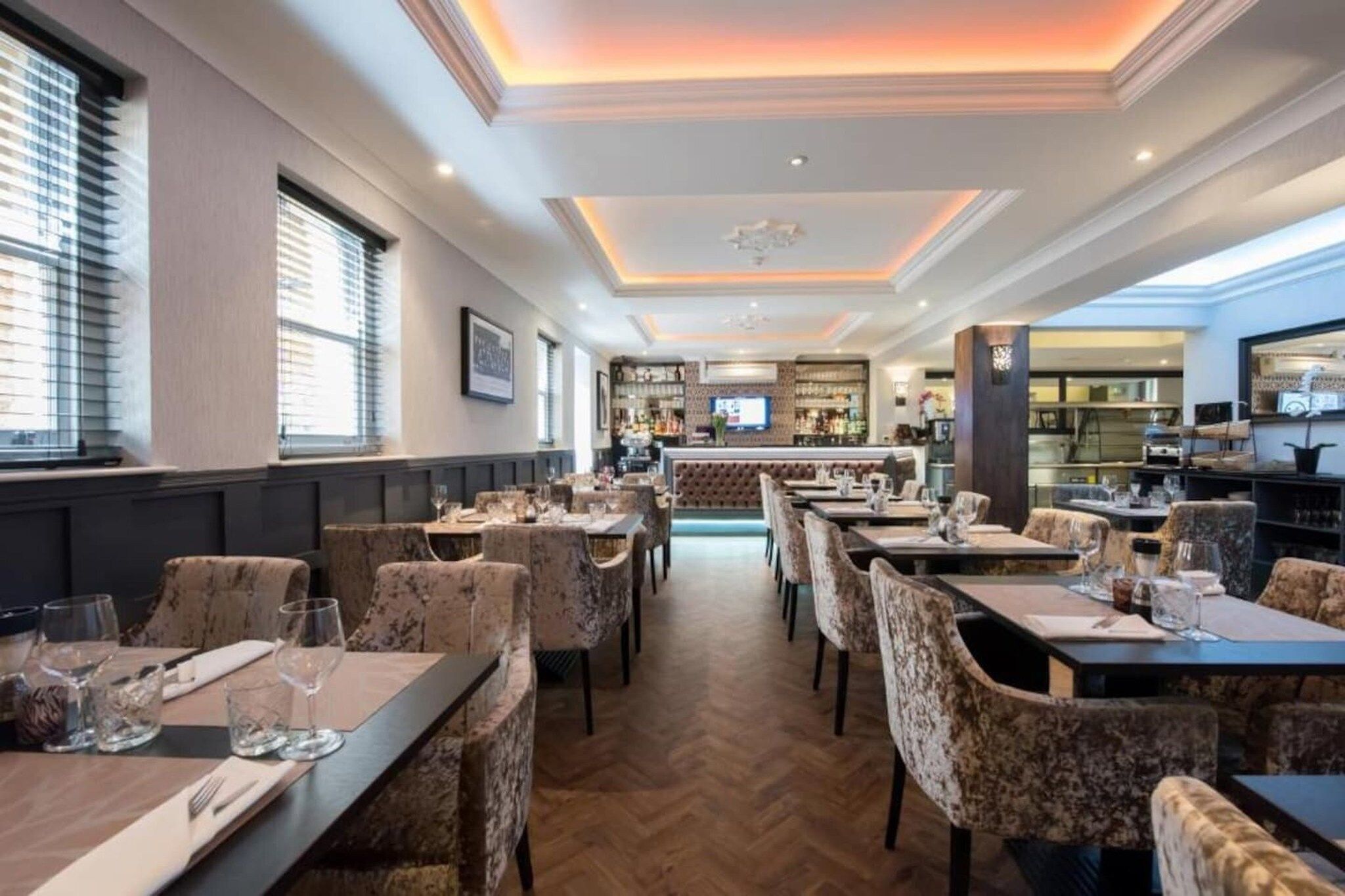 A restaurant with a bar area, multiple dining tables, and chairs.
