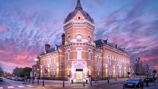 Un edificio histórico con una torre destacada, ventanas amplias y una entrada bien iluminada.