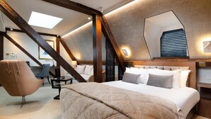 Un dormitorio con una cama grande, un escritorio, una silla y un tragaluz.