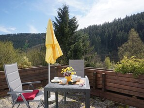 Ein Sitzbereich im Freien mit Tisch, Stühlen und einem gelben Sonnenschirm.