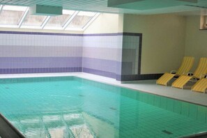 An indoor swimming pool with clear water, tiled walls, and yellow sun loungers. - Holiday apartment with 1 bedroom (Ostseebad Binz)