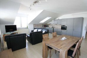A modern apartment with a dining area, kitchen, and living space. - Holiday apartment with 1 bedroom (Ostseebad Binz)