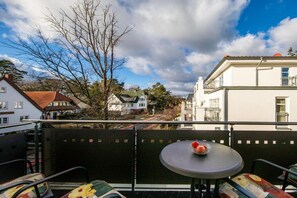 A balcony with a table and chairs, overlooking a residential area with houses and trees. - Holiday apartment with 1 bedroom (Ostseebad Binz)