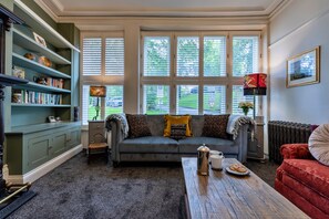 A cozy living room with a grey sofa, a wooden coffee table, and a bookshelf. - Finest Retreats | Hall Bank (Buxton)