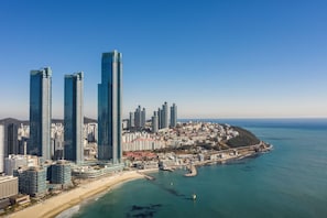 A coastal cityscape with high-rise buildings, a beach, and a pier. - LCT Residence the Drayton (Busan)