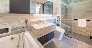 A modern bathroom with a freestanding bathtub, a granite countertop sink, a glass shower enclosure, and a toilet. - LCT Residence the Drayton (Busan)