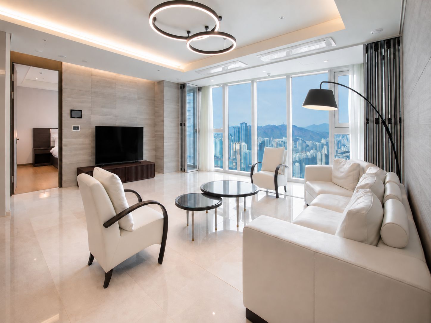 A modern living room with a flat-screen TV, a sofa, two armchairs, and a coffee table.