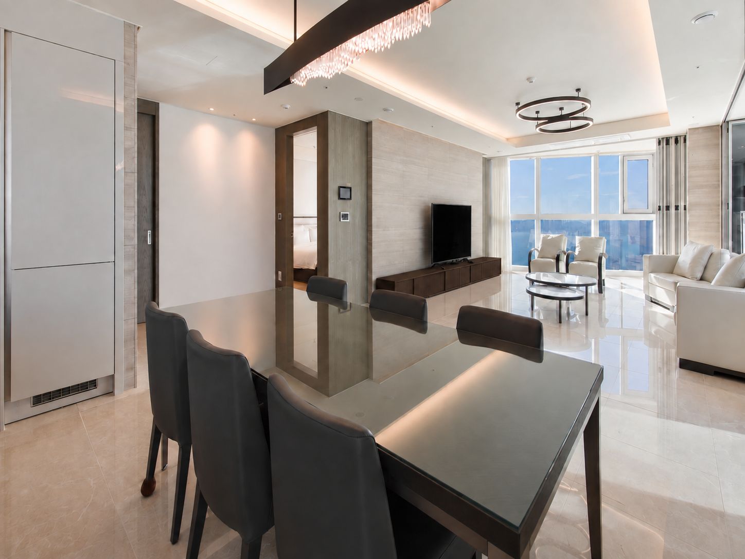 Una sala de estar moderna con una mesa de vidrio, sofás y un televisor.