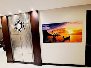 Eine Wand mit einem Zierpaneel und einem Gemälde von einem Sonnenuntergang über dem Wasser.