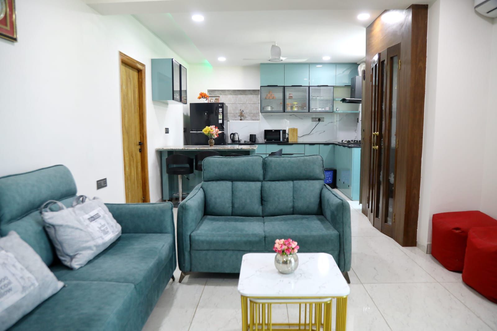 Una sala de estar con sofá, una mesita de centro y una cocina al fondo.