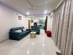 A living room with a sofa, a coffee table, and a kitchen in the background. - Miron Hotels & Resorts (Hyderabad)