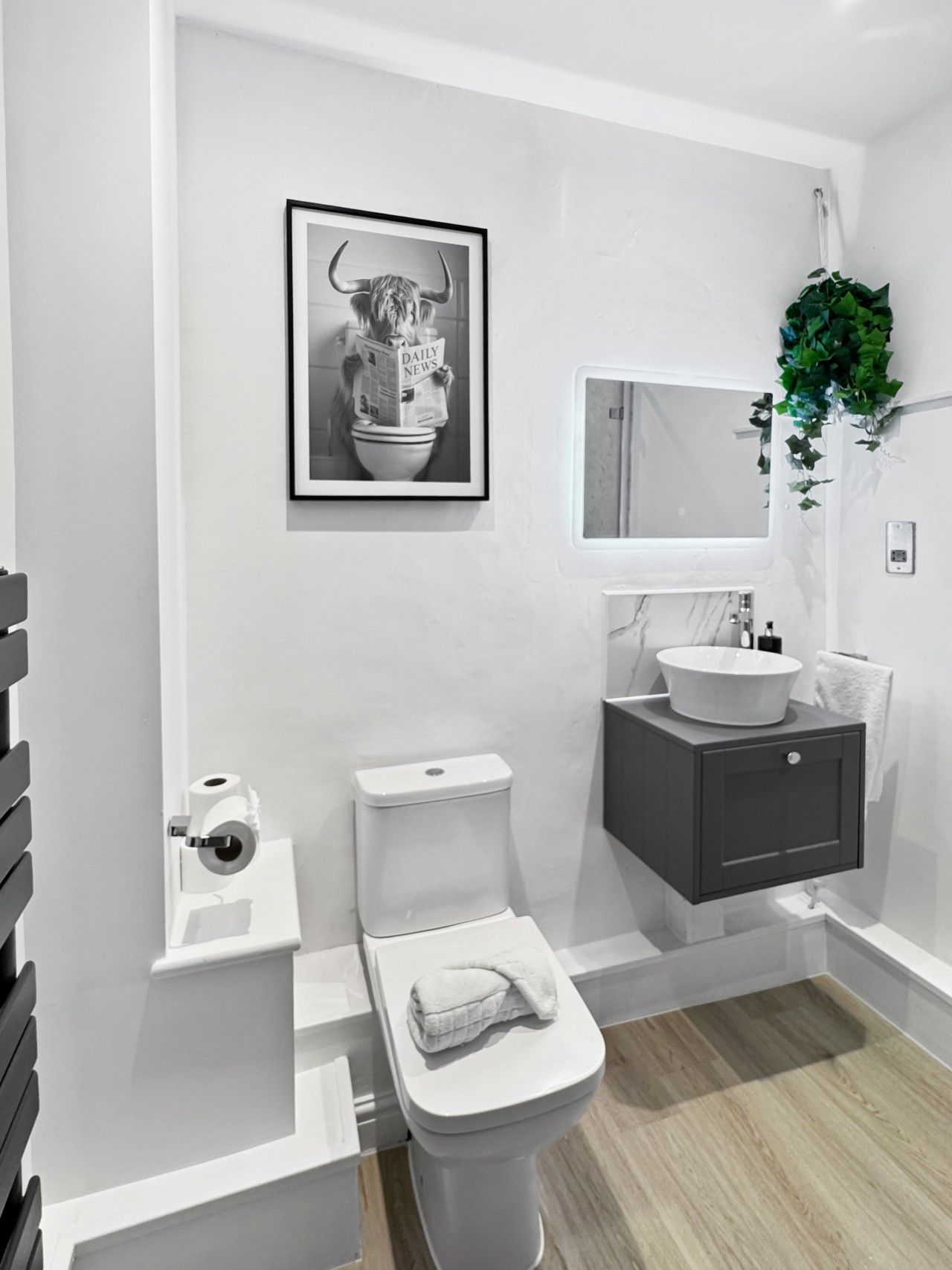 A modern bathroom with a toilet, sink, and a framed picture on the wall.