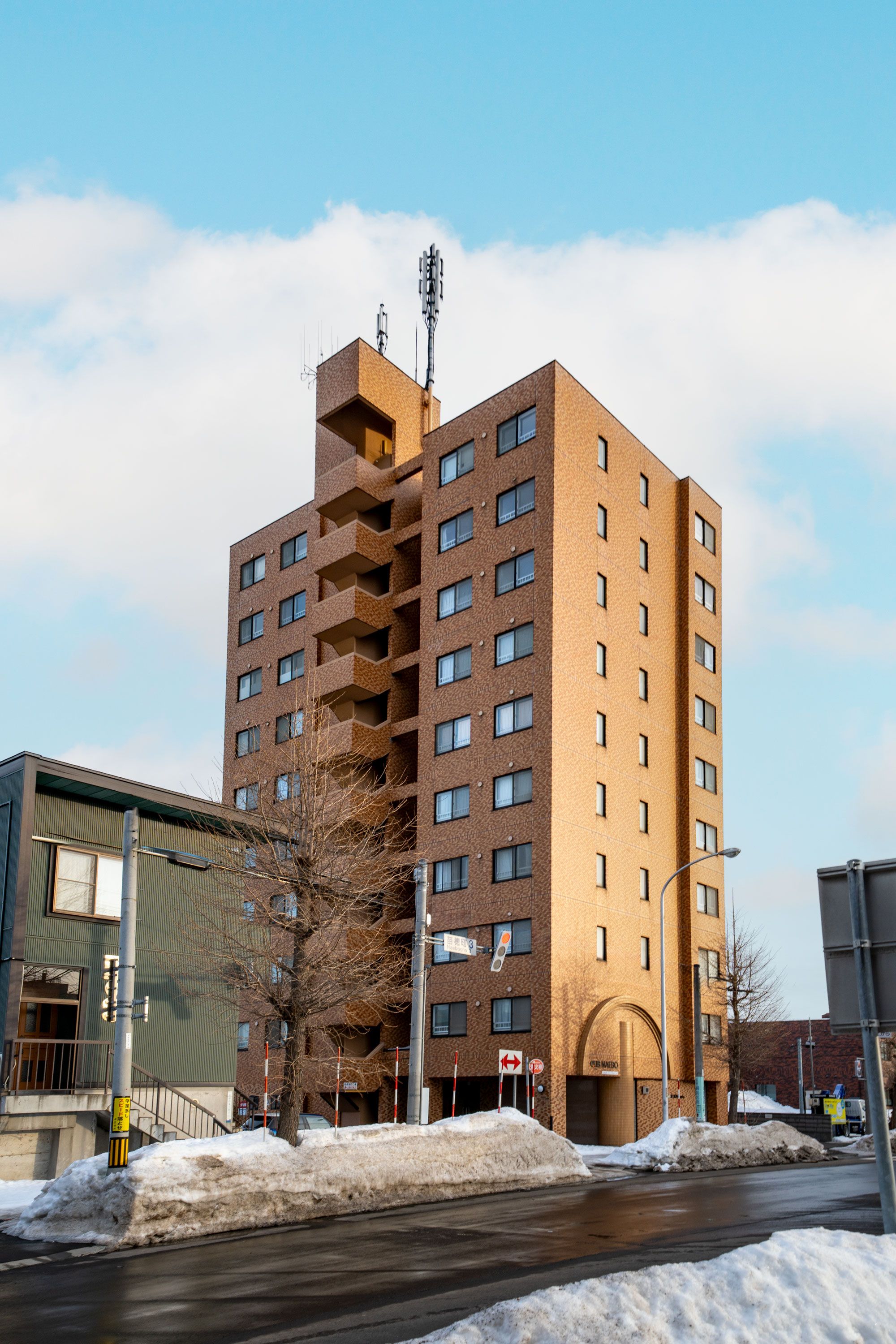 A multi-story building with a brick facade, a visible entrance, and a clear sky.