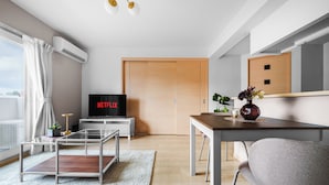 A modern living room with a flat-screen TV, a wooden door, a dining table, and a sofa. - E-US Naebo 403 (Sapporo)