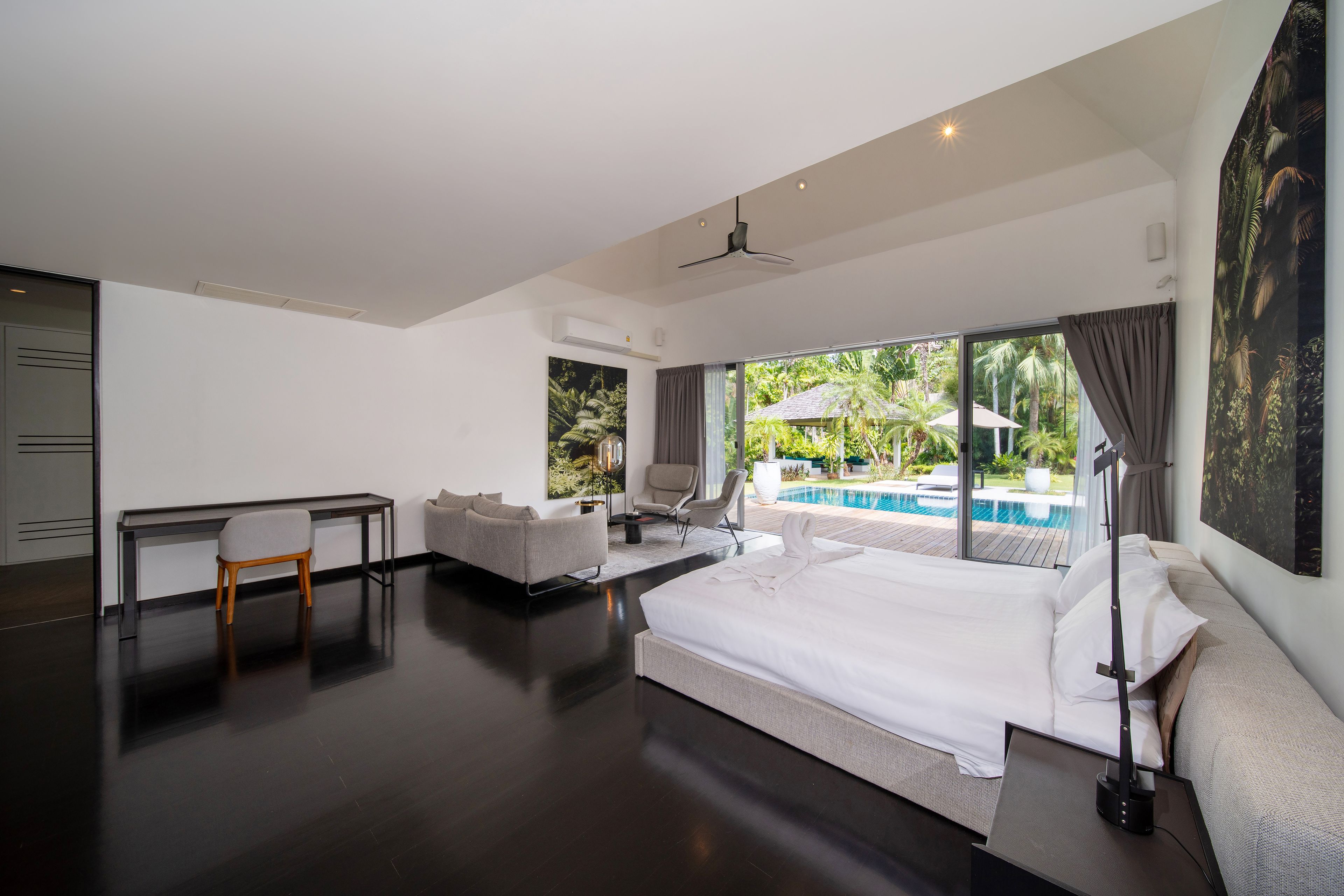 Une chambre d’hôtel moderne dotée d’un grand lit, d’un bureau, d’une chaise et offrant une vue sur une piscine extérieure.