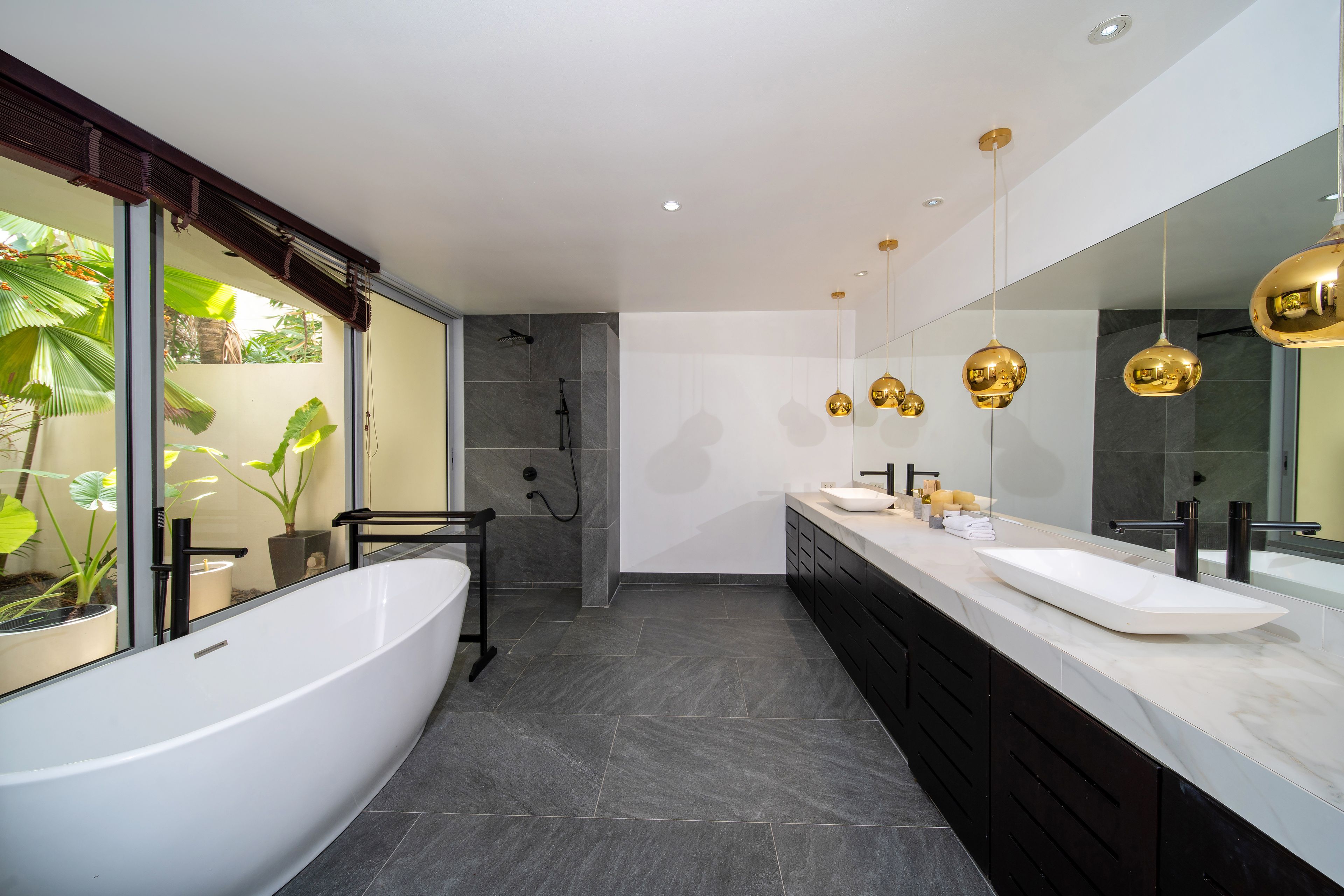 A modern bathroom with a freestanding bathtub, dual sinks, and a large mirror.