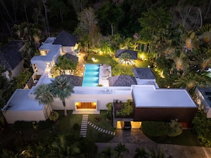 Resort com vários edifícios, piscina e vegetação tropical exuberante.
