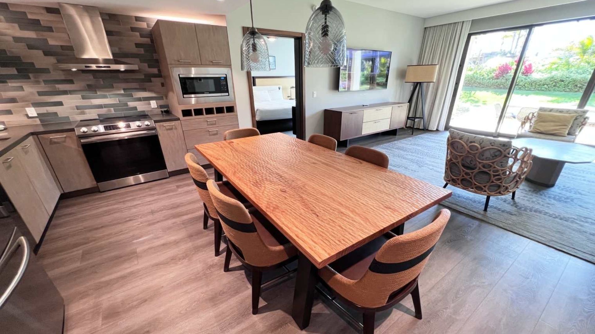A modern kitchen with a built-in microwave, stainless steel appliances, and a wooden dining table with chairs.