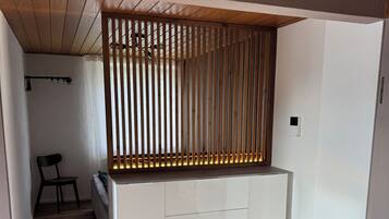 Ein modernes Interieur mit Holzboden, einer weißen, eingebauten Sitzbank mit Schubladen und einer Raumtrennung aus Holzlatten.