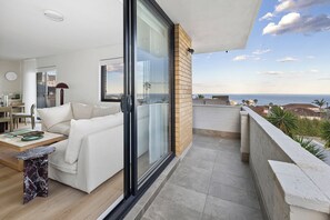 A balcony with a sofa, a dining table, and a view of the sea. - Design-Led Escape – Bondi & Tamarama – 2BR with Ocean Views (Bondi)