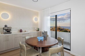 A modern kitchen with a round dining table, light wood cabinets, and a view of the ocean through large windows. - Design-Led Escape – Bondi & Tamarama – 2BR with Ocean Views (Bondi)