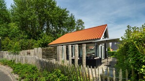 Een modern huis met een pannendak, een houten schutting en een terras.