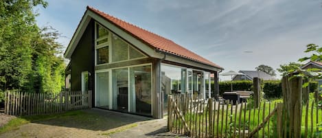 A modern house with a sloped roof, large glass windows, and a wooden fence.