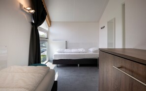 A modern hotel room with a bed, a bedside table, a wardrobe, and a window with curtains. - Zonnedorp 13 villa for seaside holidays near the beach (Renesse)