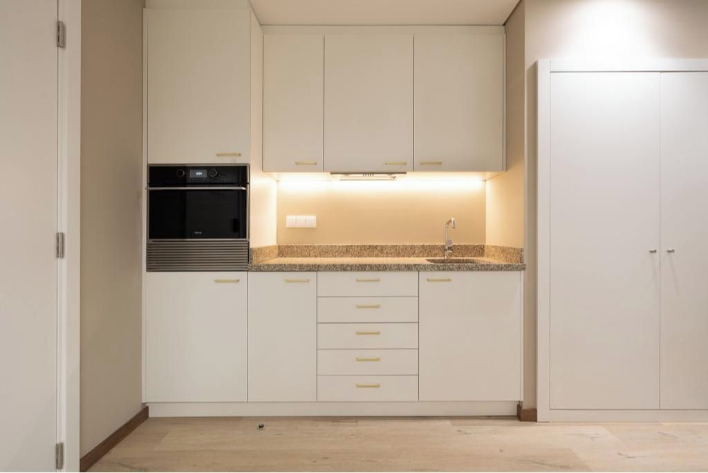 A kitchen with white cabinets, a built-in oven, and a granite countertop.