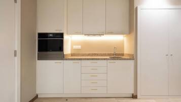 A kitchen with white cabinets, a built-in oven, and a granite countertop.