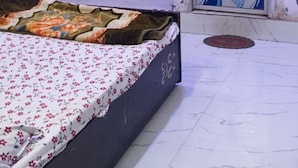 Un dormitorio con cama, ventana con cortinas, equipo de aire acondicionado y pared con puerta decorada.