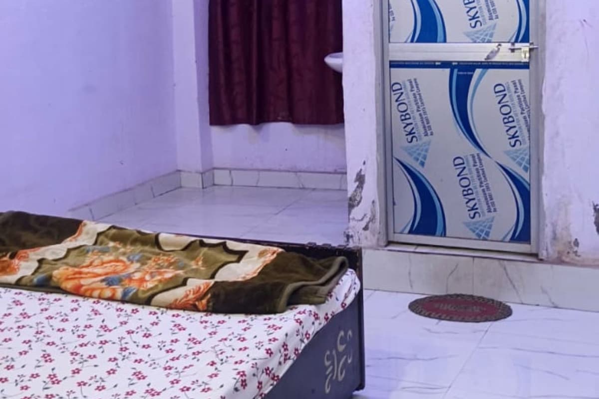 Un dormitorio con cama, ventana con cortinas, equipo de aire acondicionado y pared con puerta decorada.