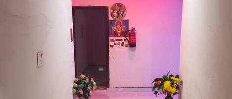 Un pasillo con ventilador de techo, extintor y dos arreglos florales.